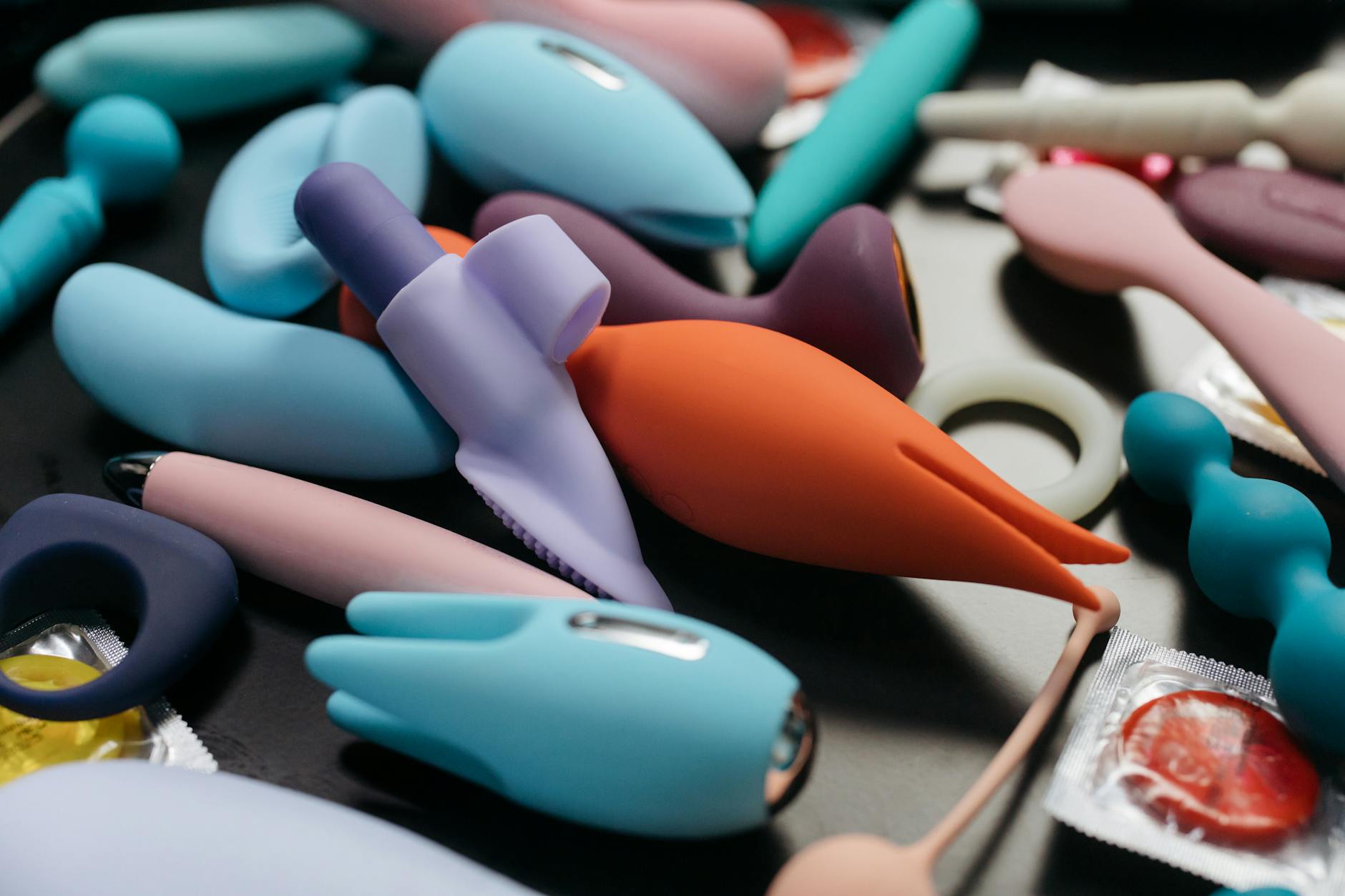 Woman holding blue and pink silicone vibrators in a contemplative manner